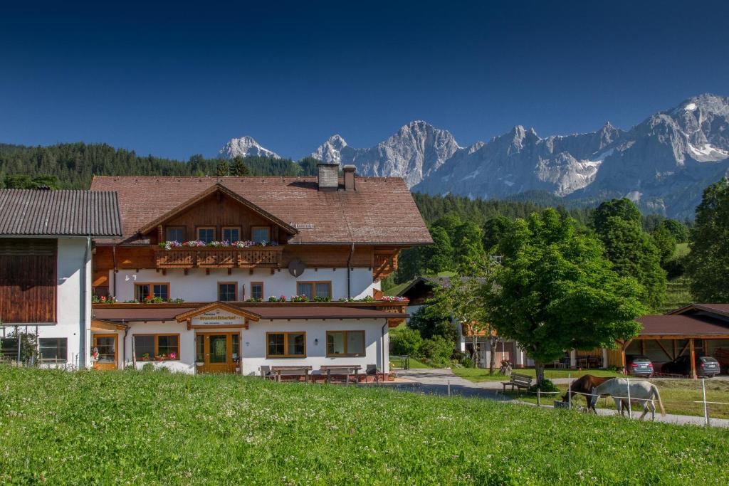 ein Haus auf einem Hügel mit Bergen im Hintergrund in der Unterkunft Brandstätterhof in Schladming