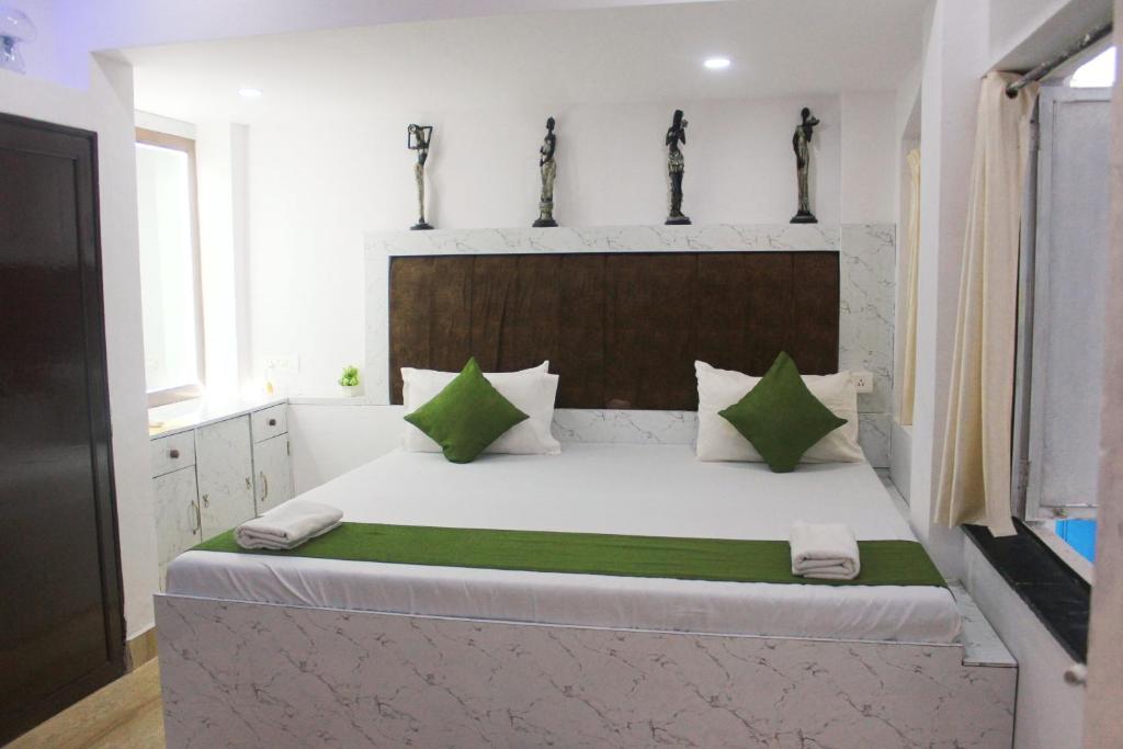 a bedroom with a large white bed with green pillows at VILLA CASA SUMANJO (3BHK) in Calangute