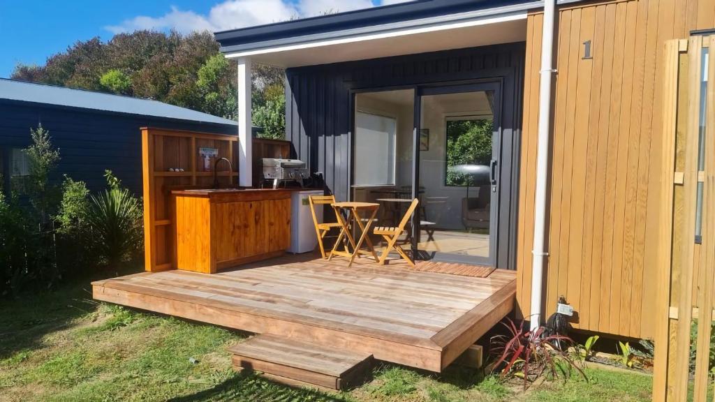 a tiny house with a wooden deck next to a building at Beach Break Cabin 1 in Pohara