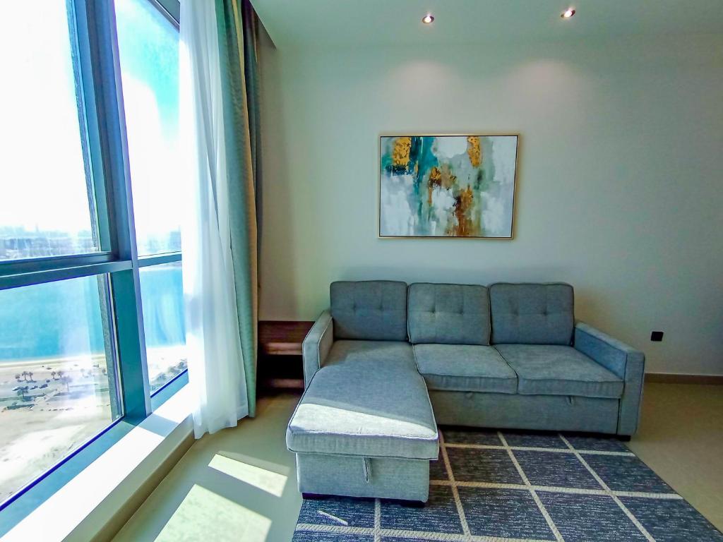a living room with a couch and a large window at Luxury 1 Bedroom Flat with Dubai Coastline View in Sharjah