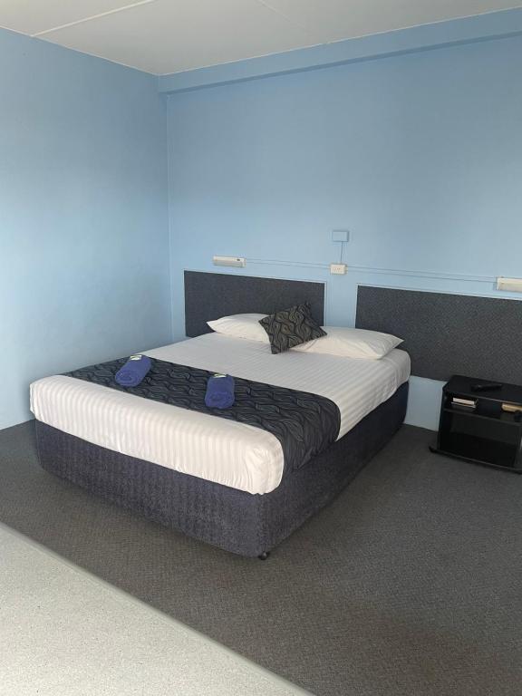 a large bed in a room with a blue wall at Springsure Hotel Motel in Springsure