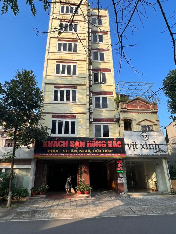 a tall building with a sign in front of it at Khách Sạn Hồng Hảo in Lao Cai