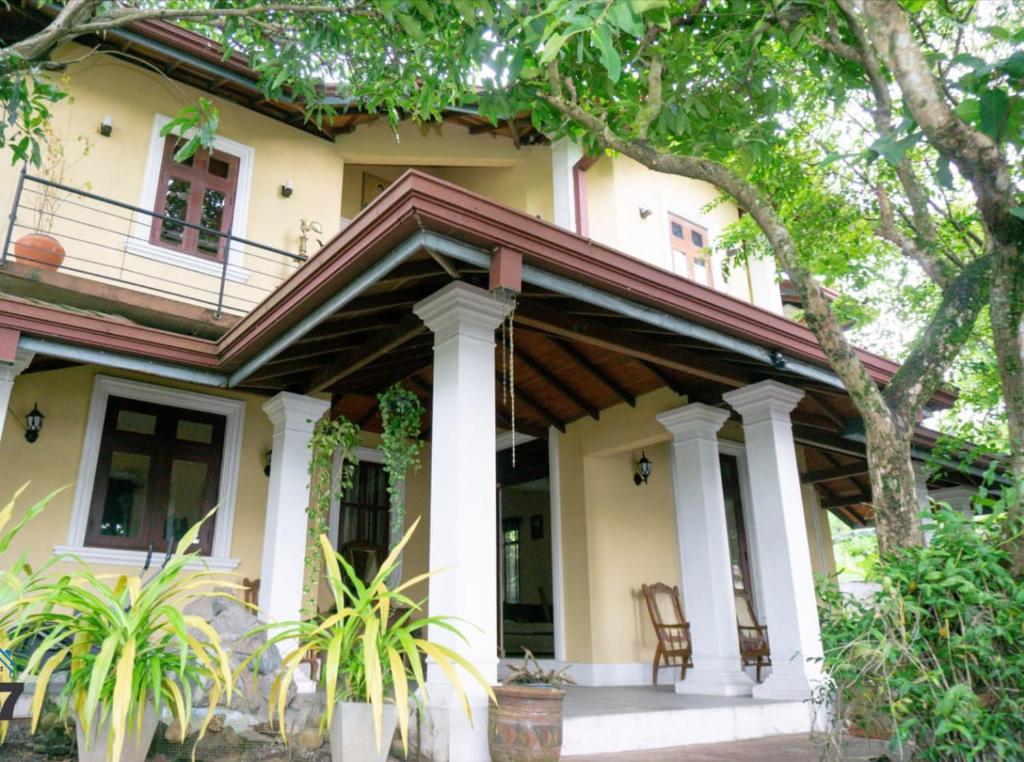 a yellow house with a porch and a tree at Airport Villa D 87 in Katunayake