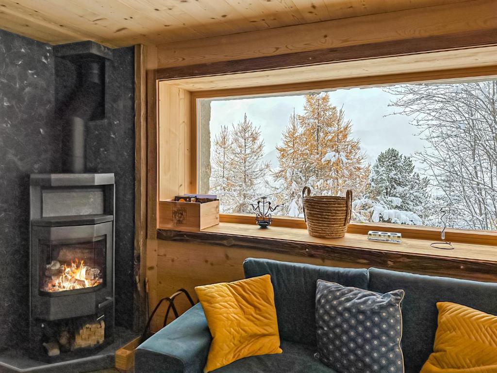 a living room with a fireplace and a couch and a window at Chalet a Didi - Alps Paradise - 4 Vallees in La Tzoumaz