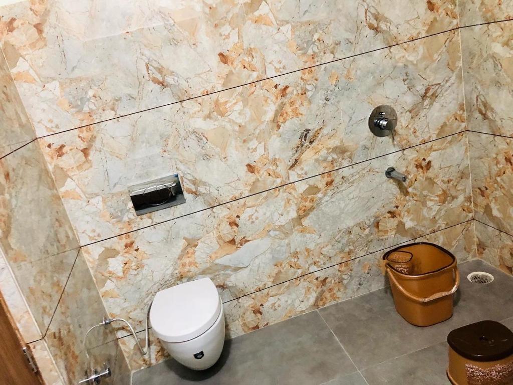 a bathroom with a toilet and a marble wall at The highclass hotel in Bathinda