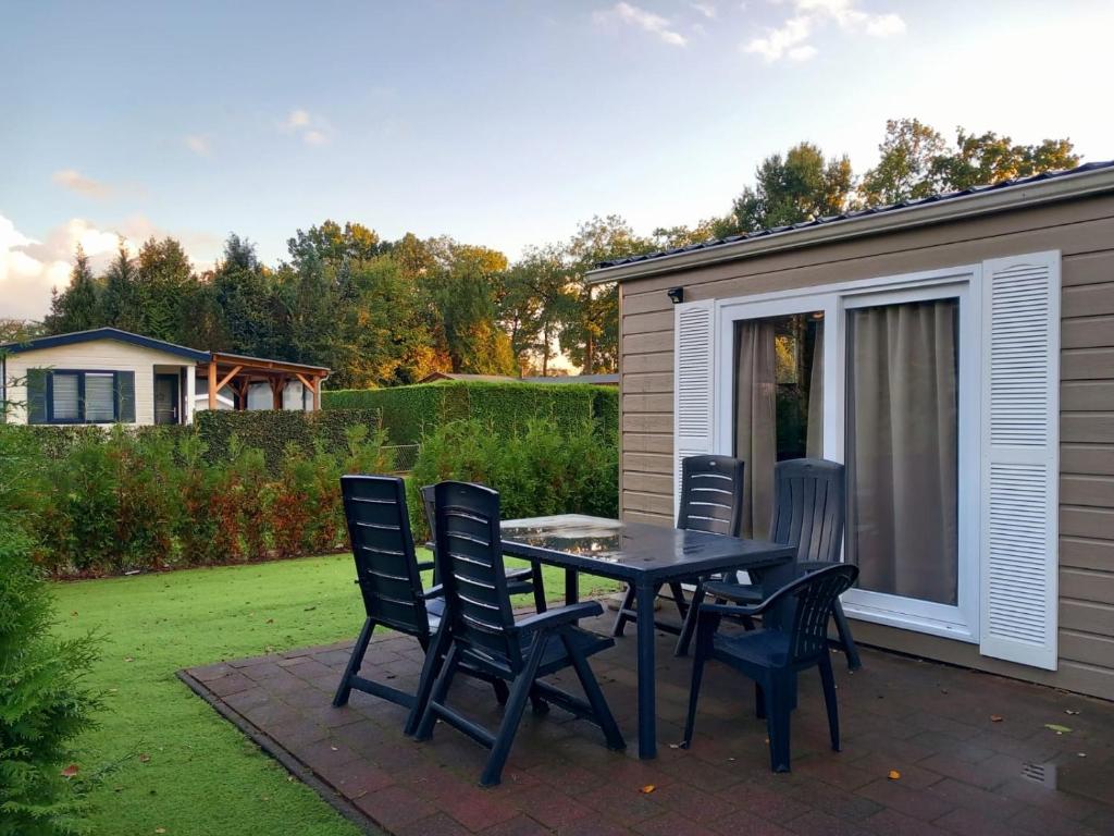 a patio with a table and chairs on a lawn at Lodge Damian op de Veluwe in Voorthuizen