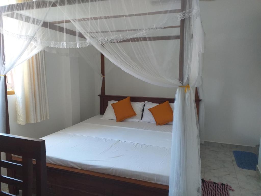 - une chambre avec un lit à baldaquin et des oreillers orange dans l'établissement Friendly House, à Galle