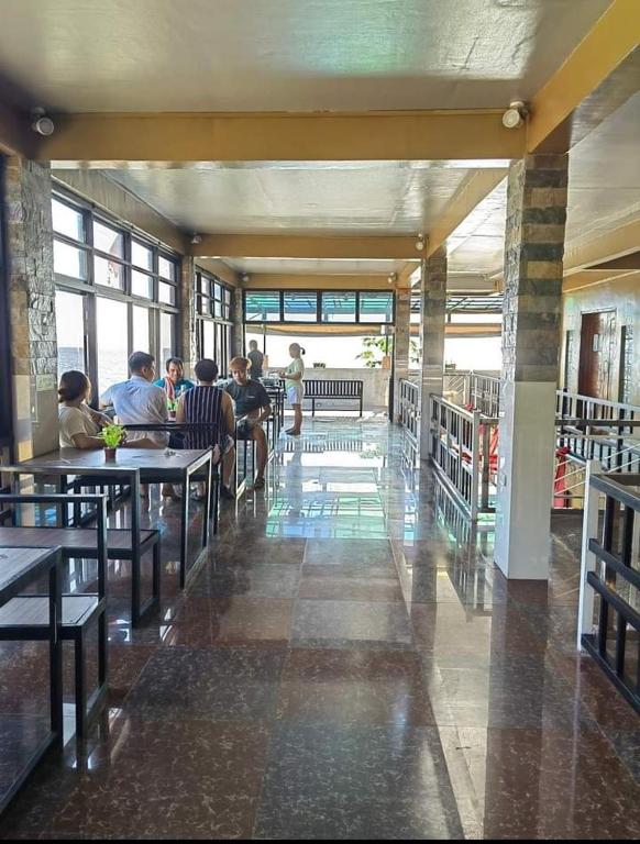 a group of people sitting at tables in a building at Ocean Myst Hotel & Beach Resort in Tambobong