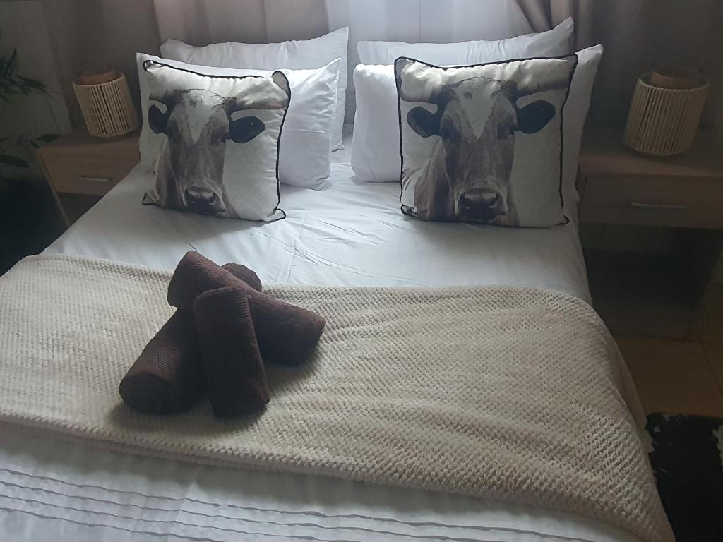 Una cama con dos almohadas con cabezas de vaca. en Mpucuko Guest House en Mtubatuba