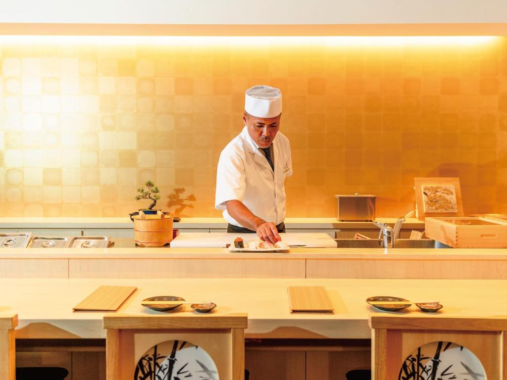 a chef standing in a kitchen preparing food at Aqua Palace Chatan by Coldio Premium in Chatan