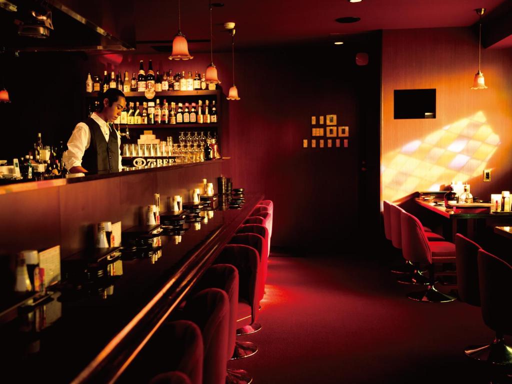 a man standing behind a bar in a restaurant at Aqua Palace Chatan by Coldio Premium in Chatan