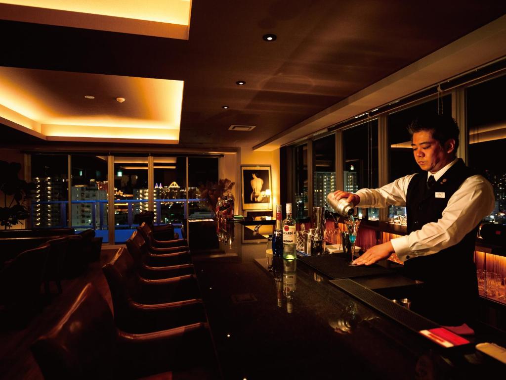 a man standing at a bar in a restaurant at Aqua Palace Chatan by Coldio Premium in Chatan