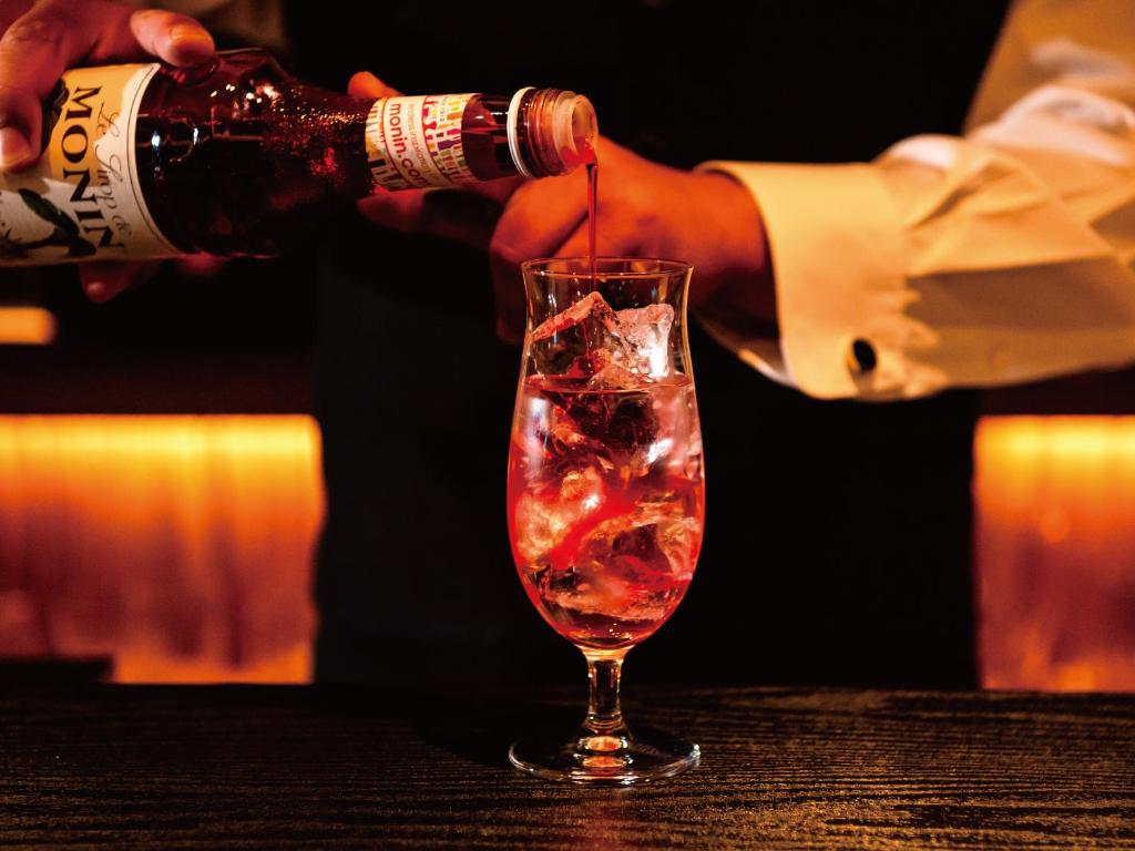a person pouring a drink into a glass at Aqua Palace Chatan by Coldio Premium in Chatan