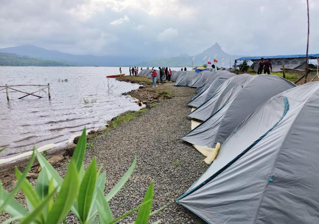 a row of tents on the shore of a body of water at Pawna lake Camping Lonavala in Kolvan