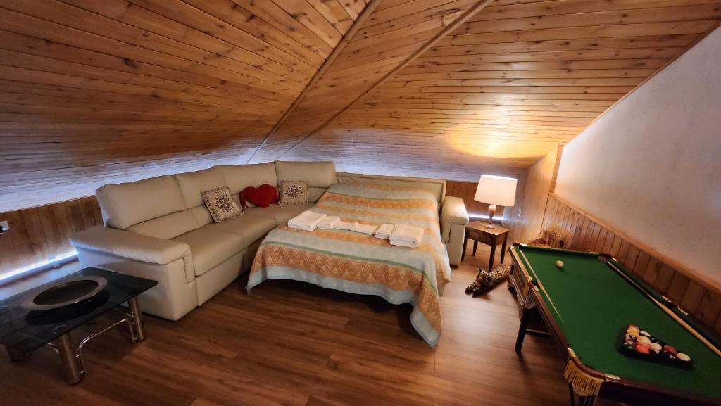 a attic room with a couch and a pool table at La Golette Apartment in La Thuile