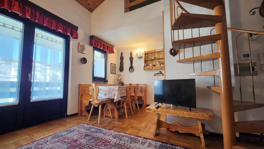 a living room with a television and a table with chairs at La Golette Apartment in La Thuile