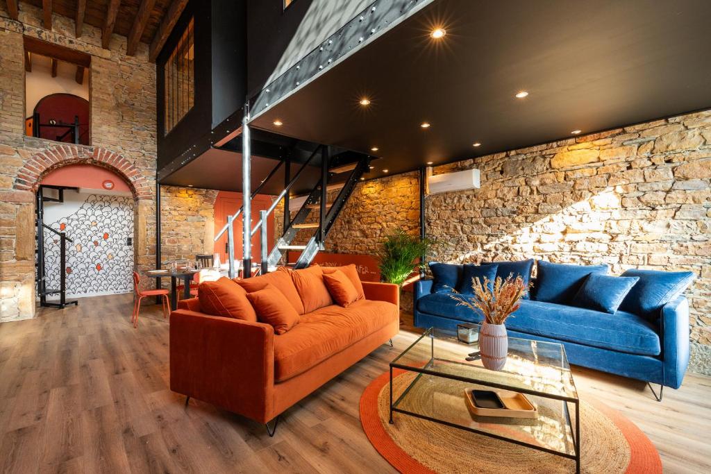 a living room with blue and orange furniture and a stone wall at SmartStay Bird Family - Lyon in Lyon