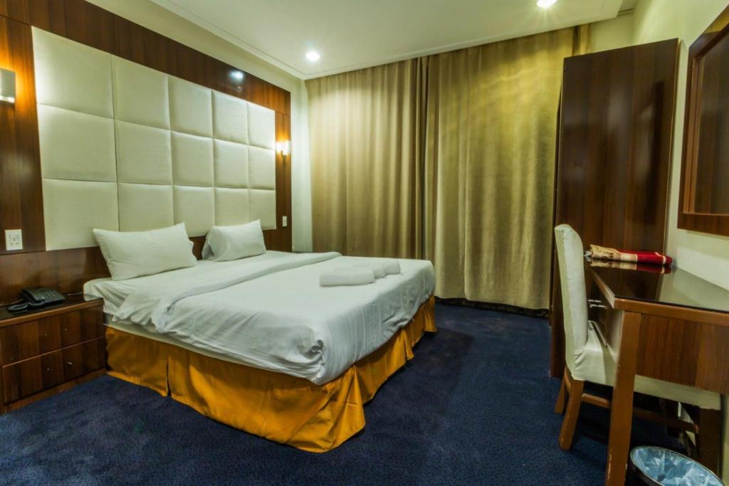 ein Schlafzimmer mit einem großen Bett und einem Schreibtisch in der Unterkunft Dar Hotel Suites in Dschidda