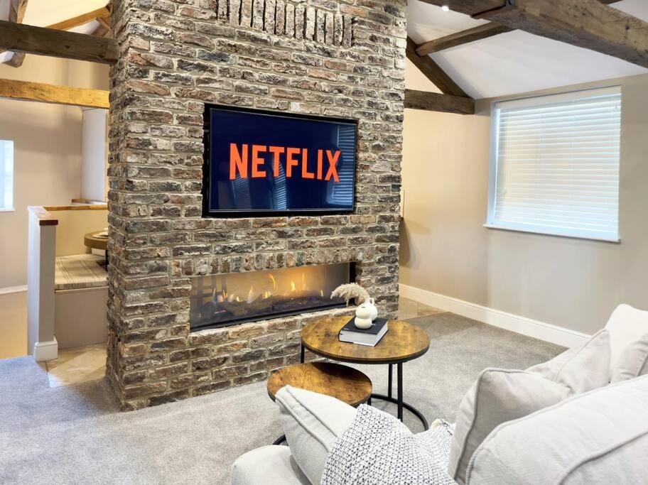 a living room with a fireplace and a tv on a brick wall at Whitkirk Cottage in Leeds