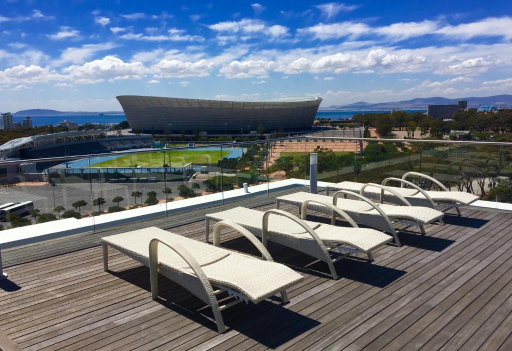 a group of white chairs on a roof with a stadium at 145 on Main - Legacy Green Point in Cape Town