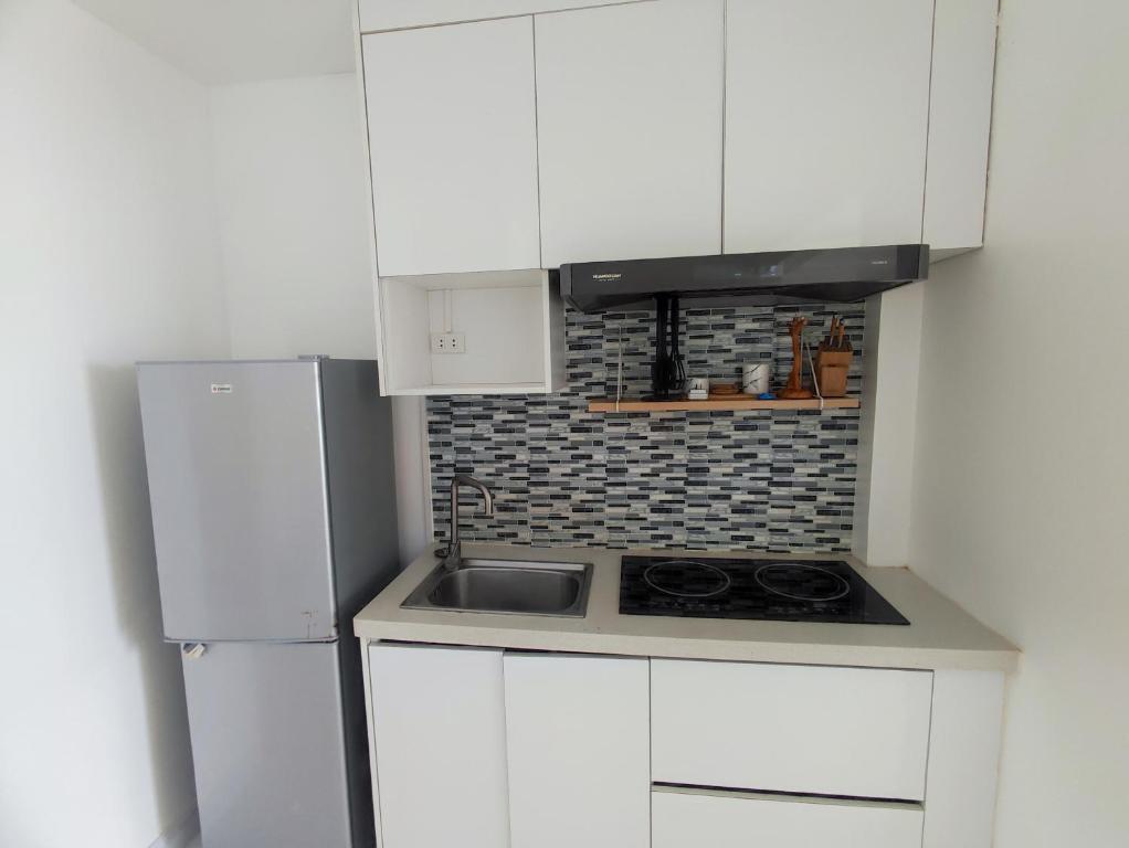 a white kitchen with a sink and a refrigerator at Seaview Emerald Adoces Beach Resort in Morong