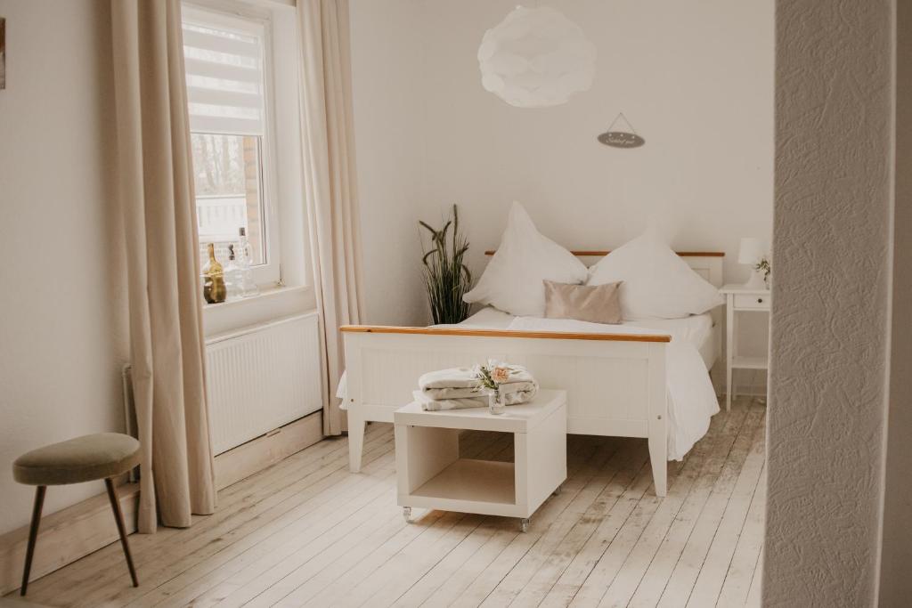 a white bedroom with a bed and a table at Ferienwohnung Häserhof in Raddestorf
