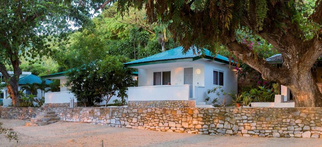 a white house with a blue roof behind a stone wall at The Three P Beach Resort & Dive Center in Romblon