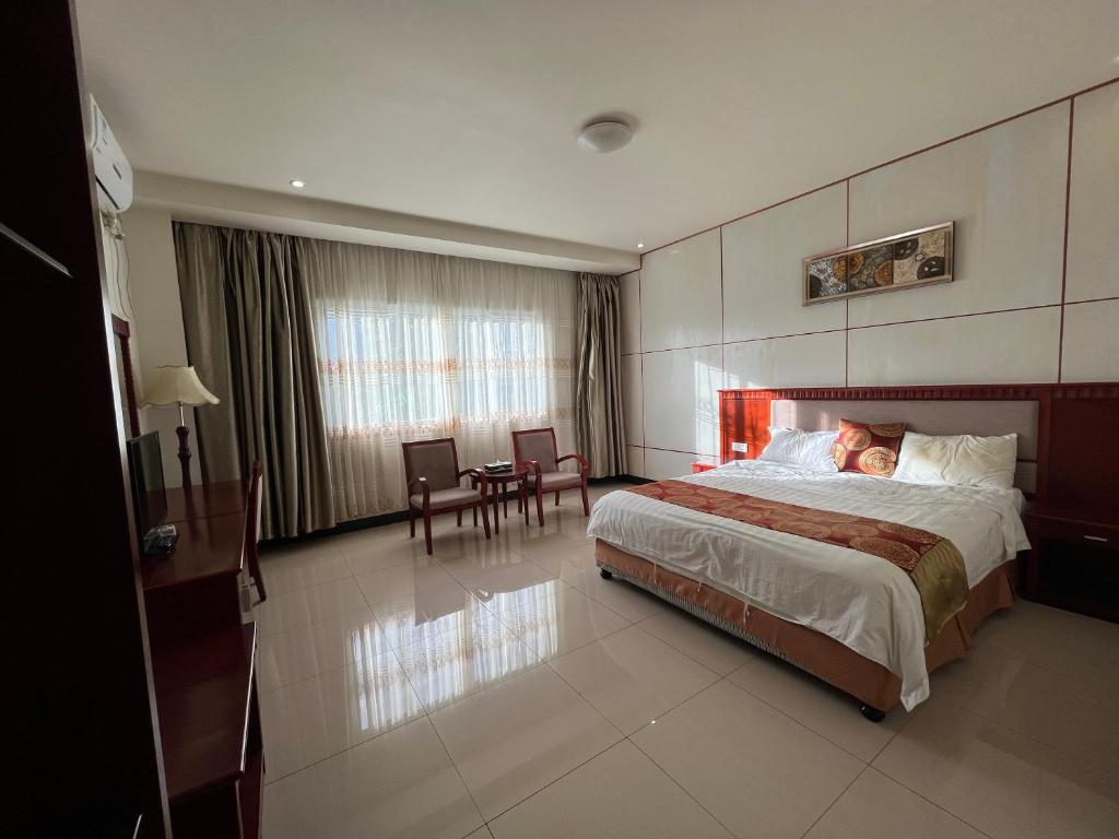 ヌクアロファにあるMeida Hotelのベッド、テーブル、椅子が備わるホテルルームです。