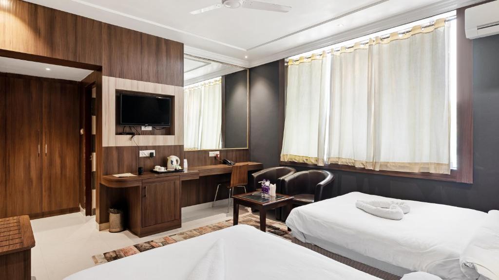 a hotel room with two beds and a desk at Niranjana Hotel Bodhgaya in Bodh Gaya