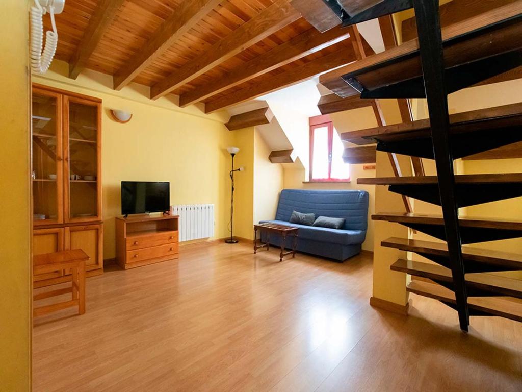 sala de estar con sofá azul y escalera en Apartamentos Canfranc 3000, en Canfranc-Estación