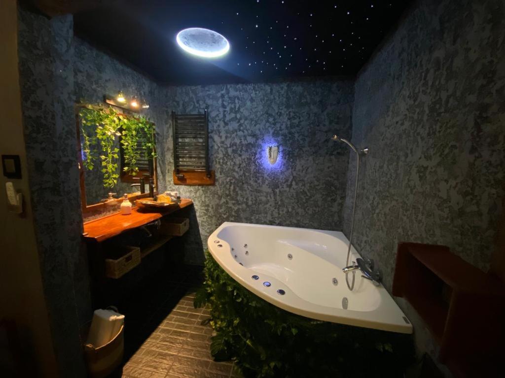 a bathroom with a large bath tub and a sink and aorescent at Tropicana Jacuzzi Apartment in Kraków