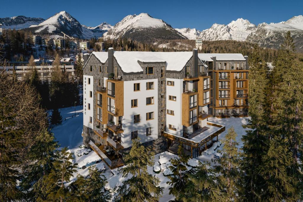 an aerial view of a building with snow covered mountains at Apartmán 107 Ovruč in Štrbské Pleso