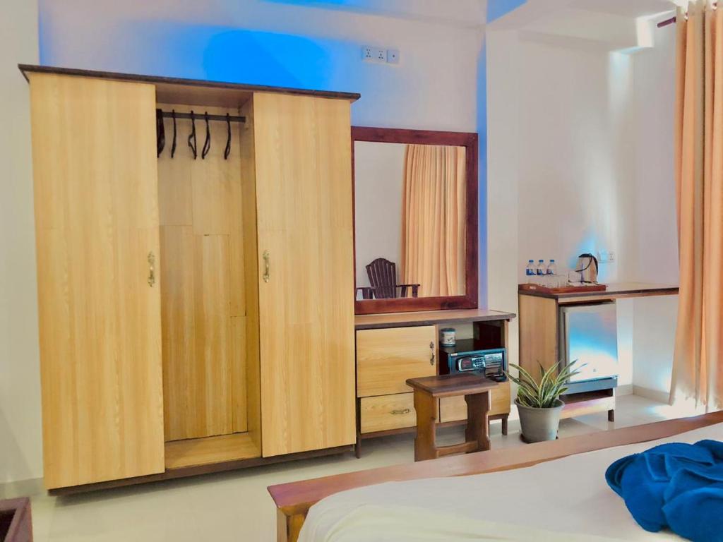 a bedroom with a large wooden cabinet with a desk at Mirissa Beach Inn in Mirissa