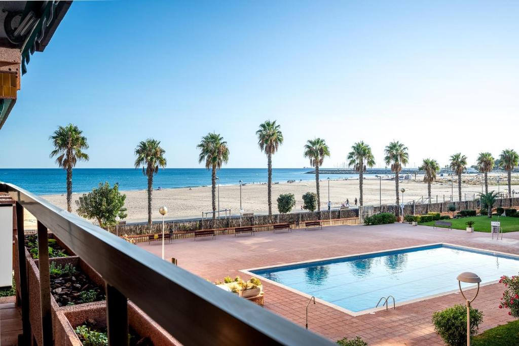 Una vista de la playa desde el balcón de un resort. en AT135 Els Pins, primera línea, piscina, muy bien equipado, en Torredembarra