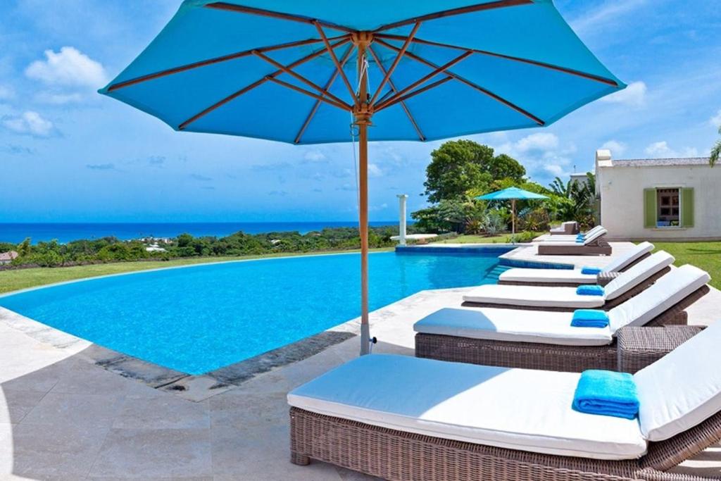 a row of lounge chairs with an umbrella next to a swimming pool at Marsh Mellow by Blue Sky Luxury in Saint James