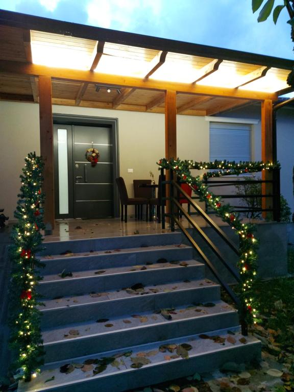 a porch with christmas lights and stairs with a christmas tree at Nicolaus Hidden Gem Villa in Shkodër