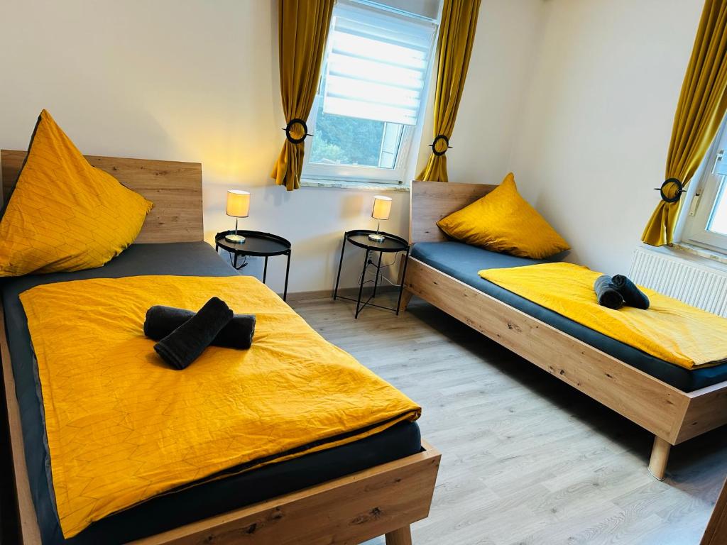 two beds in a room with yellow sheets at Gästehaus Trockau in Pegnitz