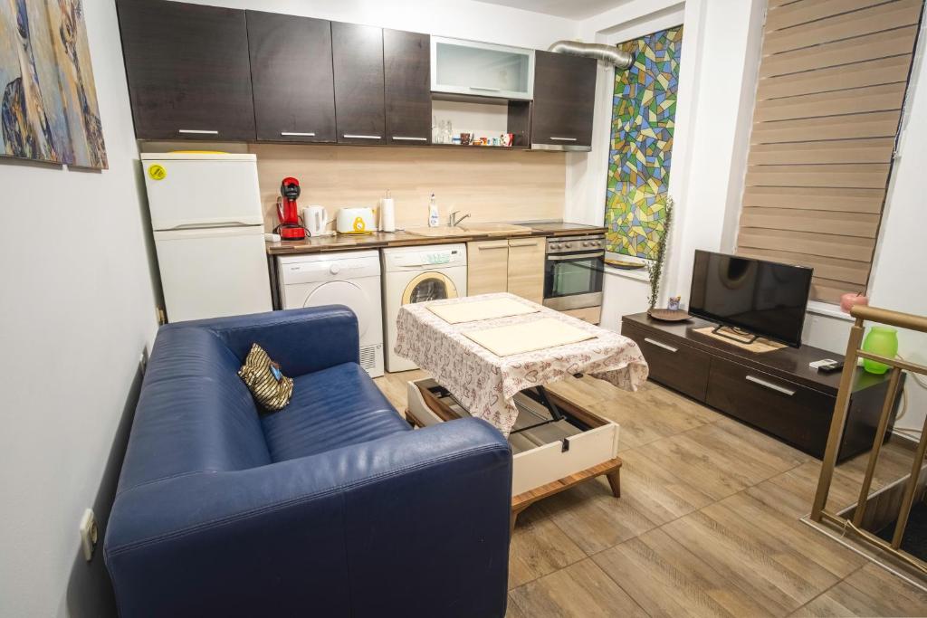 a living room with a blue couch and a kitchen at Ruse Apartment Center in Ruse