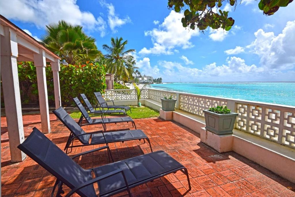 una fila di sedie su un patio con vista sull'oceano di Arcadia Blue Sky Luxury a Bridgetown