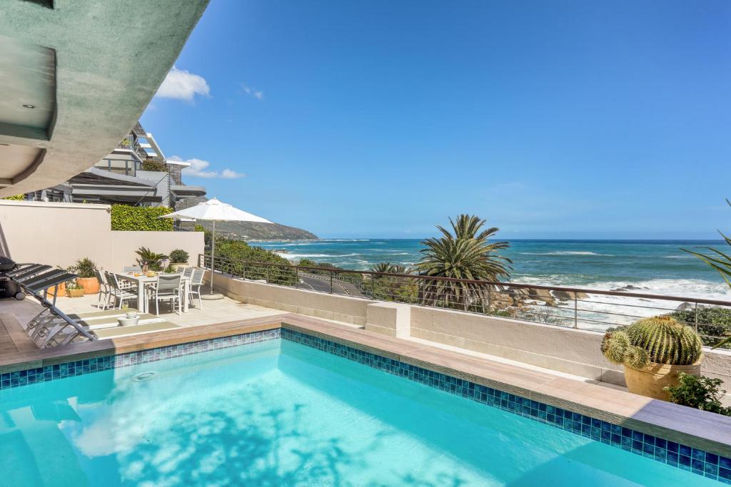 a swimming pool with the ocean in the background at Bakoven Sunsets - Luxury Apt with sea views & pool in Cape Town