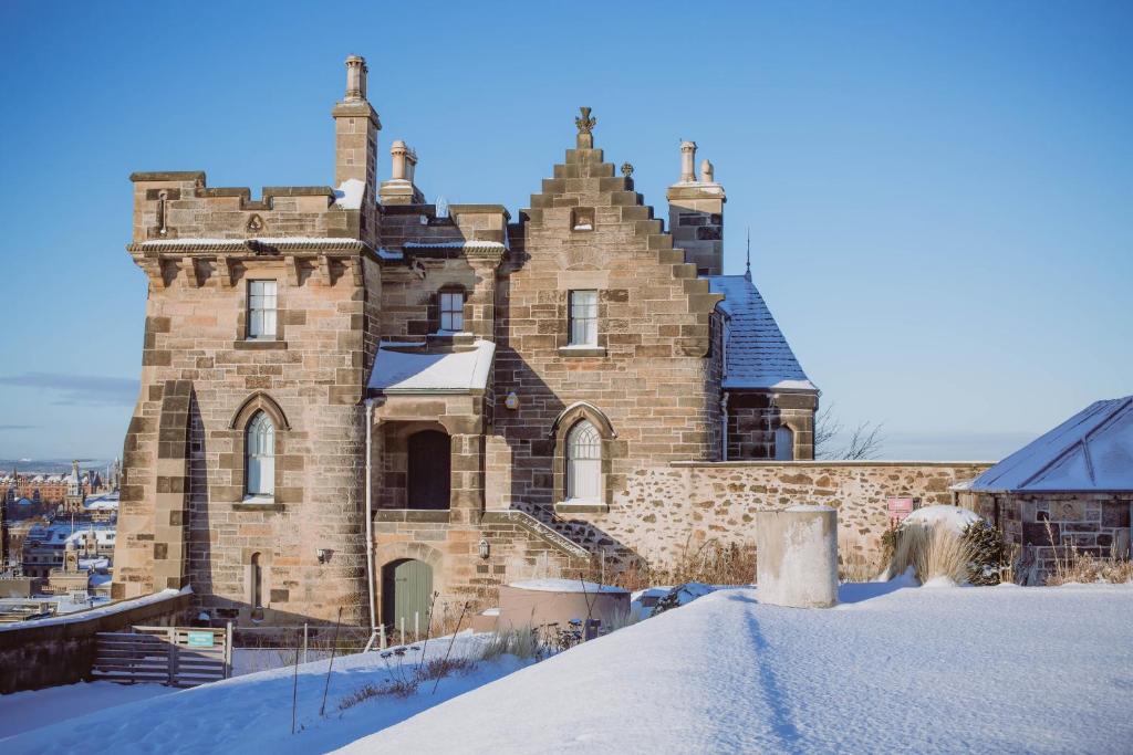 an old brick building with snow on the ground at ALTIDO Observatory House and Apartment in Edinburgh