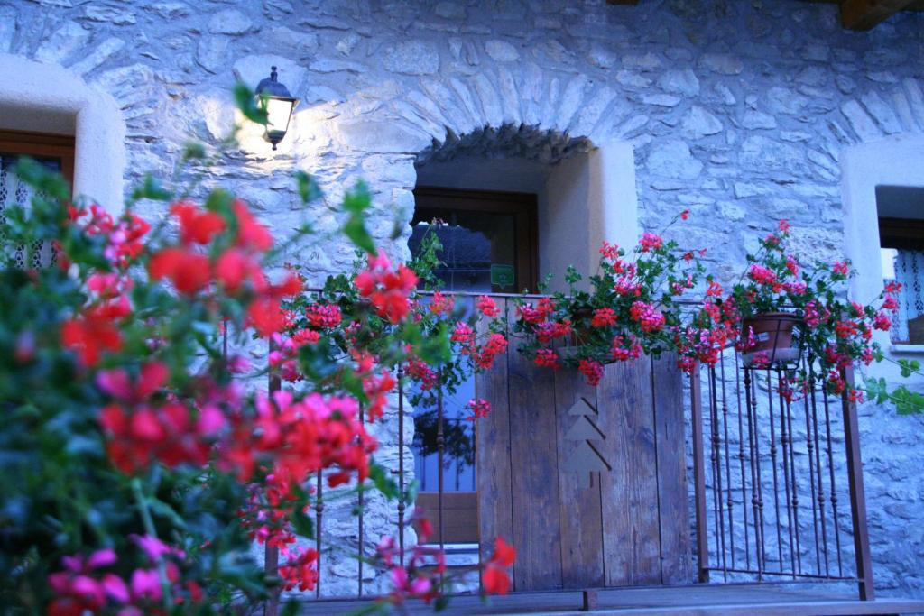 a gate with flowers in front of a stone building at Affittacamere Chez Magan in Gignod