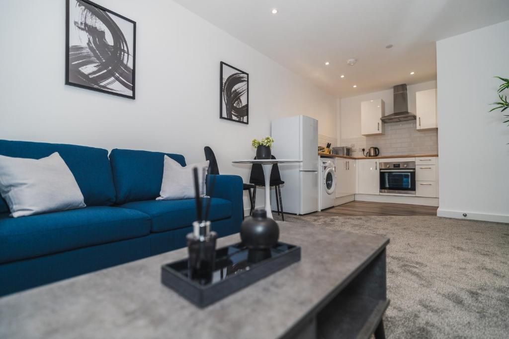 a living room with a blue couch and a kitchen at VICHY - The Thornhill City Center Apartment in Wakefield