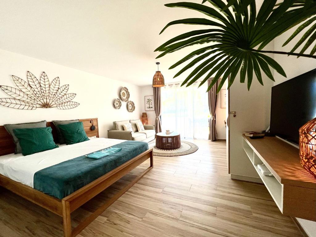 a bedroom with a bed and a large plant at Cosy studio - 2P - Orient Bay - ALAMANDA - 002 in Saint Martin
