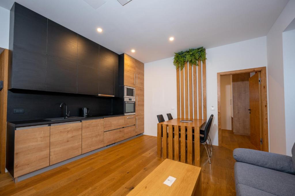 cocina con armarios negros y mesa de madera en Cirus apartments, en Kočevje