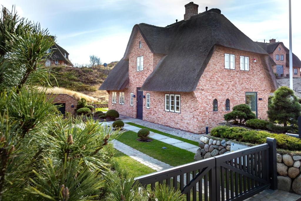 een groot bakstenen huis met een rieten dak bij Ferienhaus Heidehüs Mellhörn in List