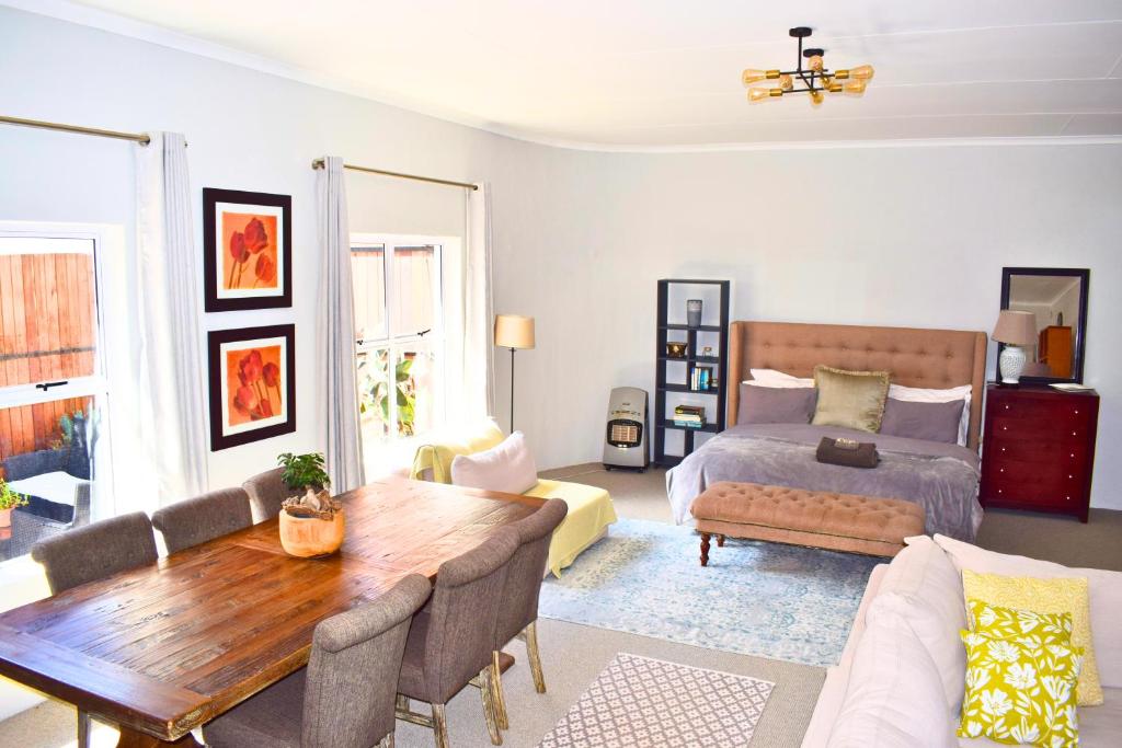 a living room with a bed and a wooden table at Riverclub Guest Suites in Riverclub, Sandton in Johannesburg