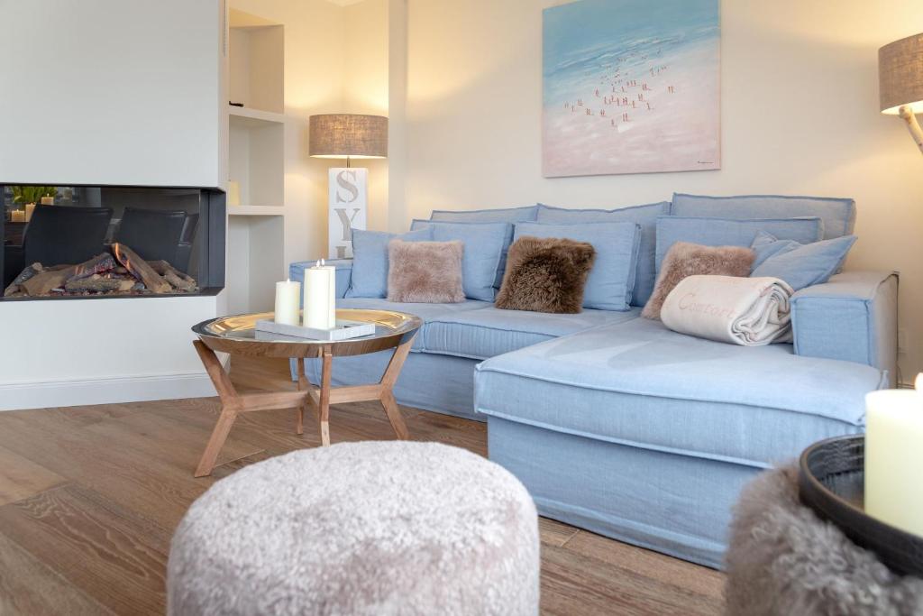 uma sala de estar com um sofá azul e uma mesa em Ferienhaus Süderhörn em List
