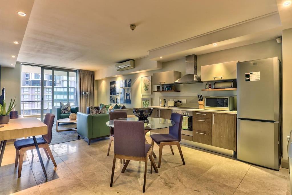 a kitchen and living room with a table and chairs at Luxury 1 Bedroom apartment in Canal Quays in Cape Town