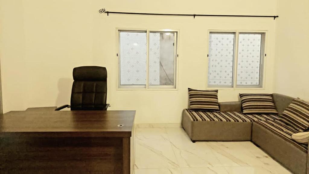 Habitación con sofá, escritorio y silla. en Belle loge de 5 pièces à proximité de l'aéroport en Cotonú